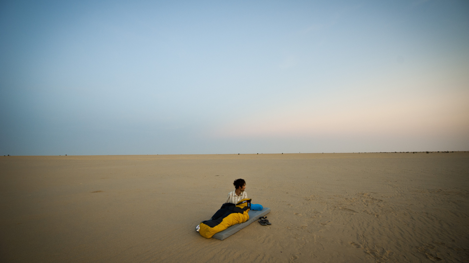 Мужчина на матрасе на пляже