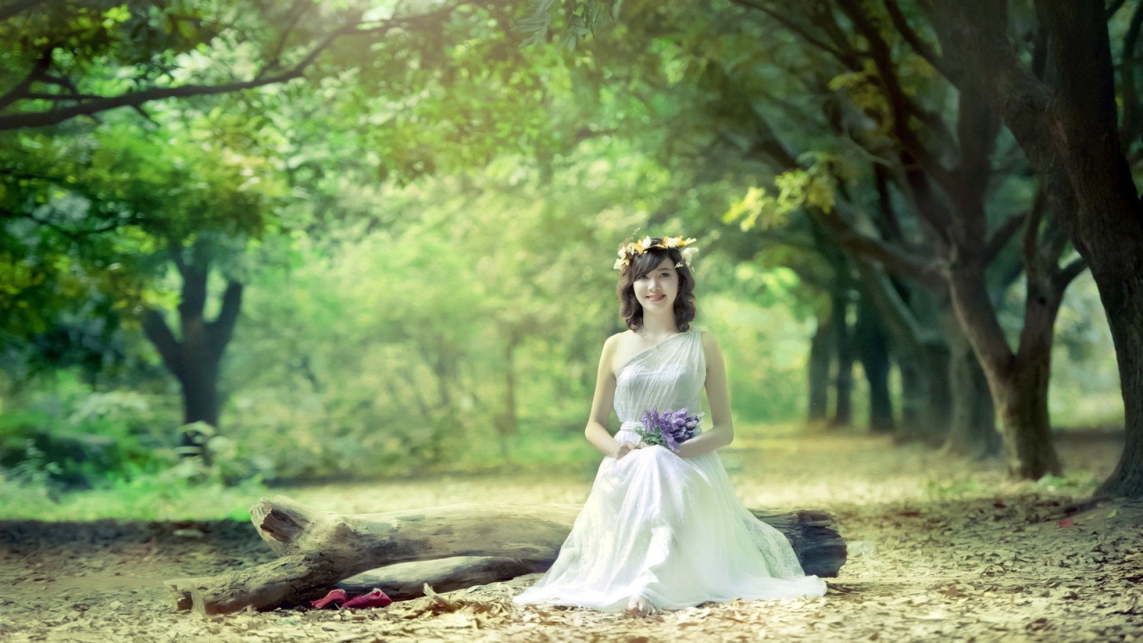 Девушка сидит на бревне