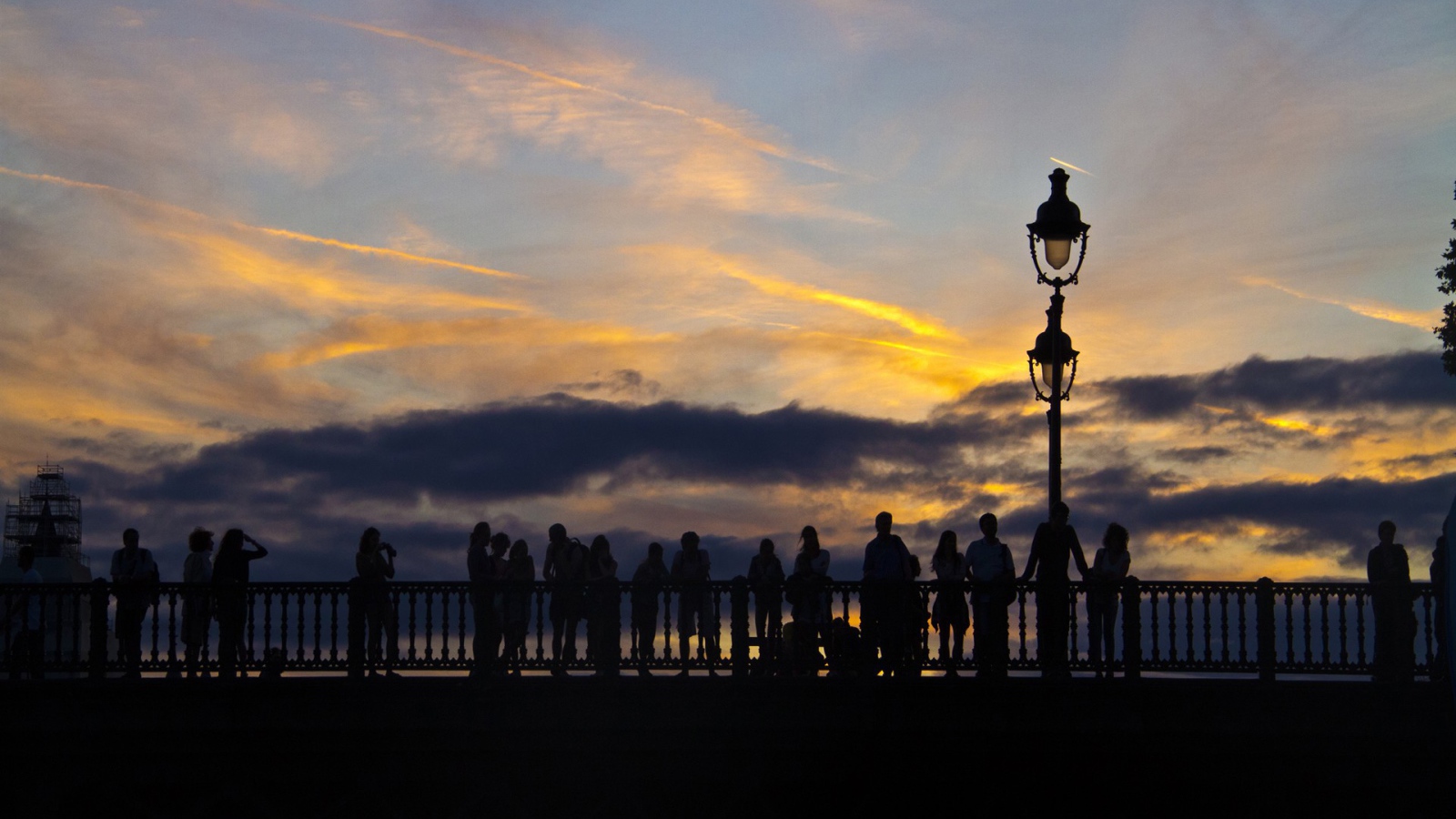 Люди провожают солнце на мосту