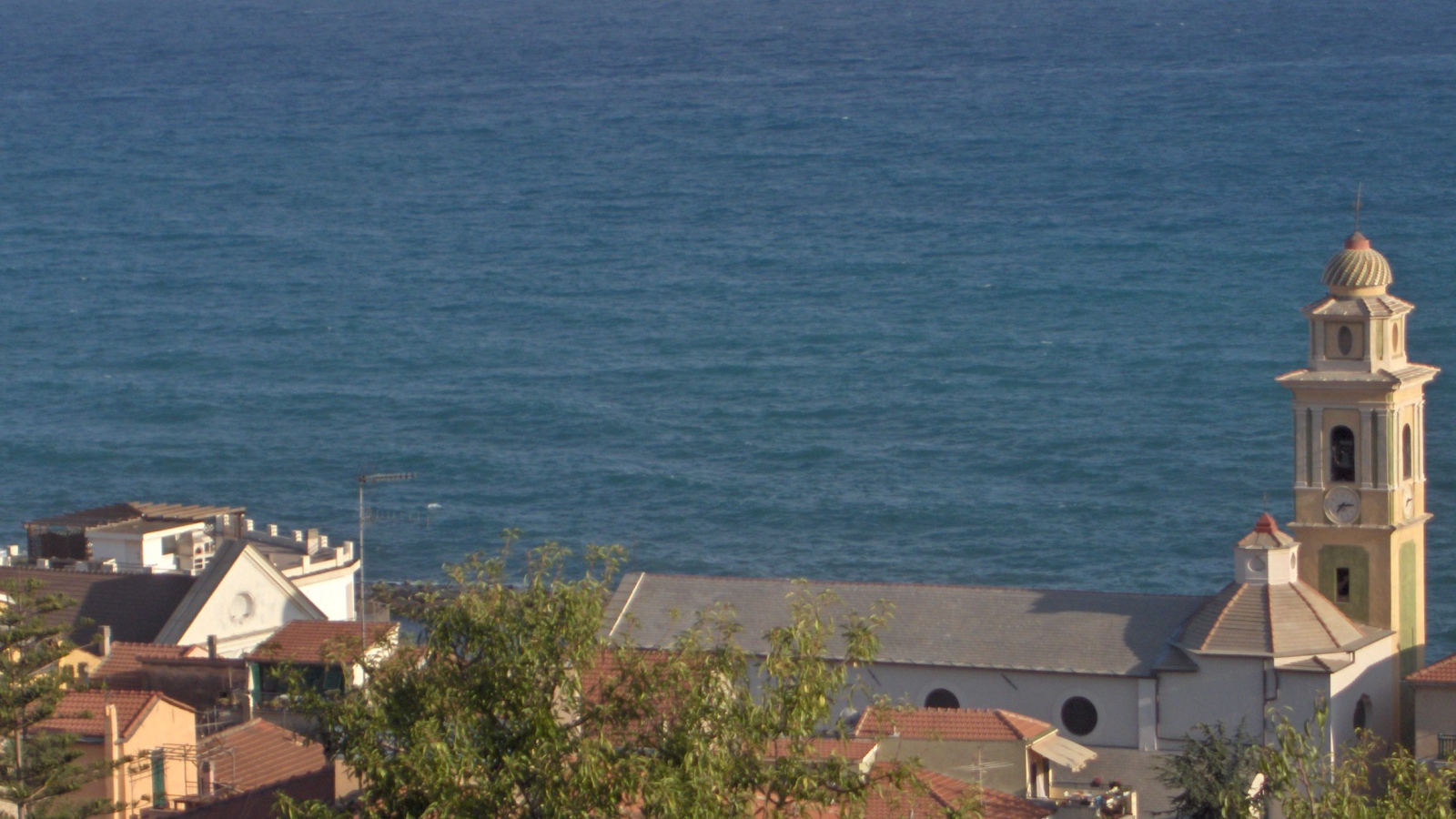 Башня с часами на фоне моря в Санто Стефано аль Маре, Италия