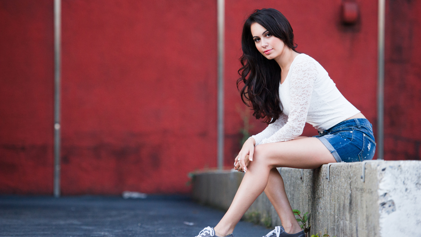 Брюнетка в кедах на бордюре