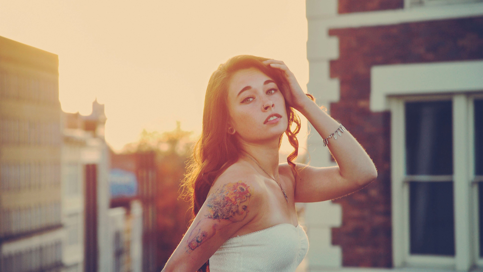 Девушка на закате с татуировкой на плече