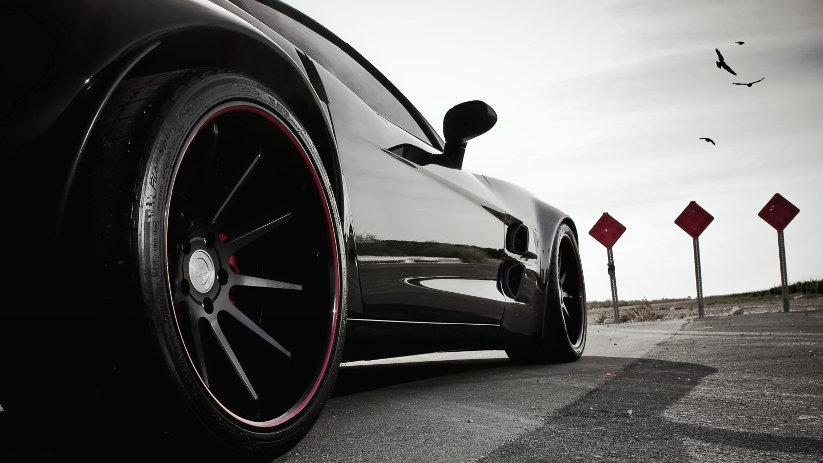 Черный автомобиль перед дорожными знаками