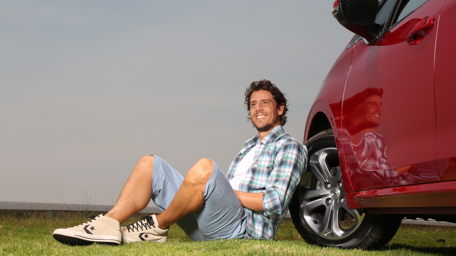 Мужчина сидит у колеса своего автомобиля