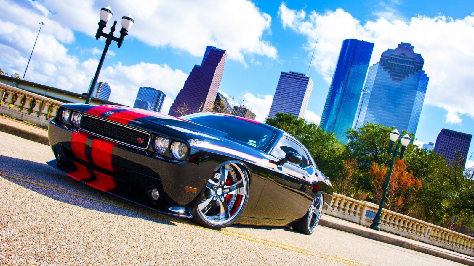 Черный Dodge Challenger с красными полосами на фоне небоскребов