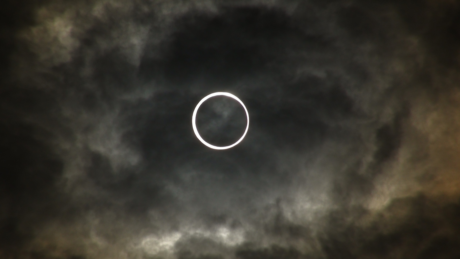 Белый круг на фоне темных облаков