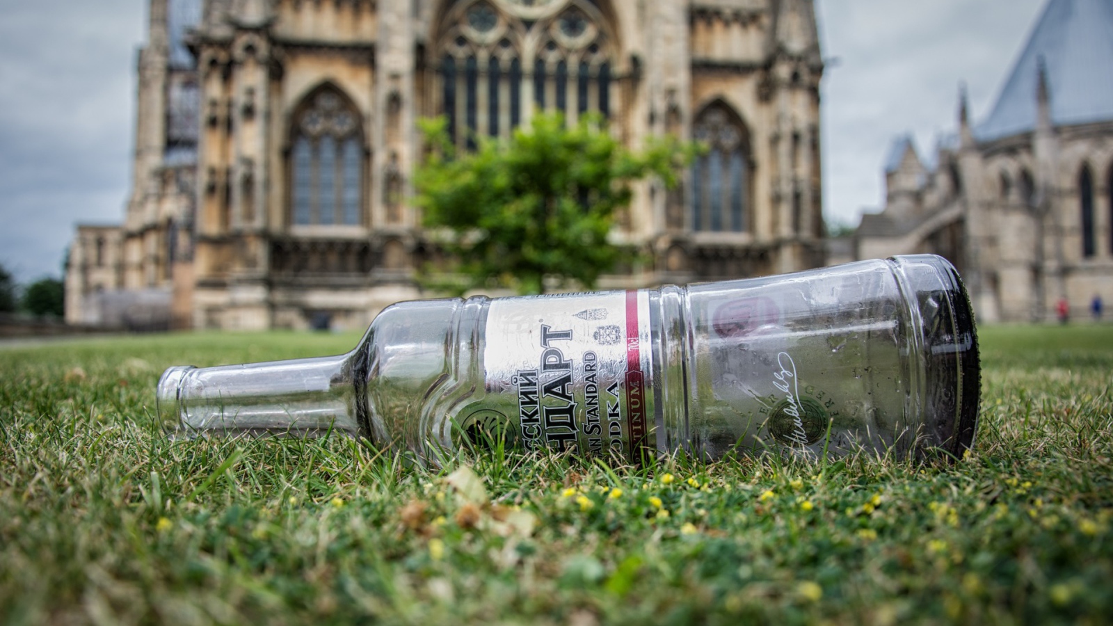Пустая бутылка на газоне перед храмом