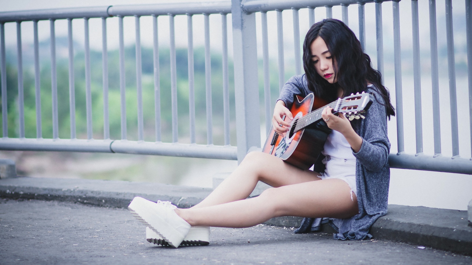 Азиатка брюнетка с гитарой на мосту