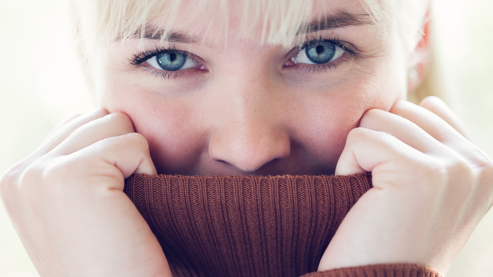 Блондинка прячет лицо в вороте свитера