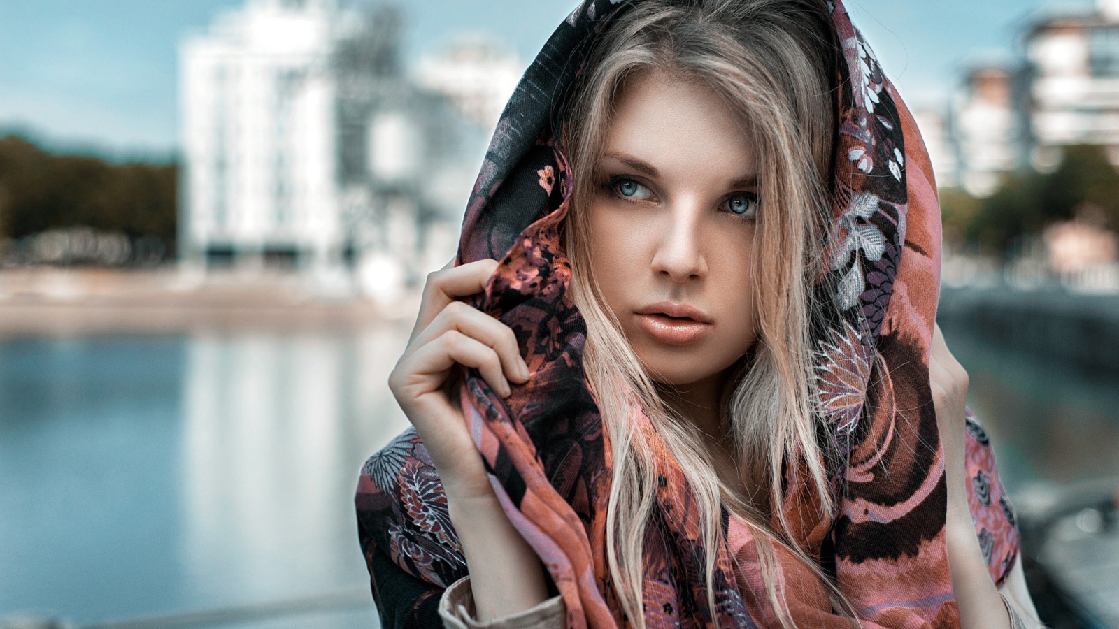 Блондинка в накидке на фоне городского пруда