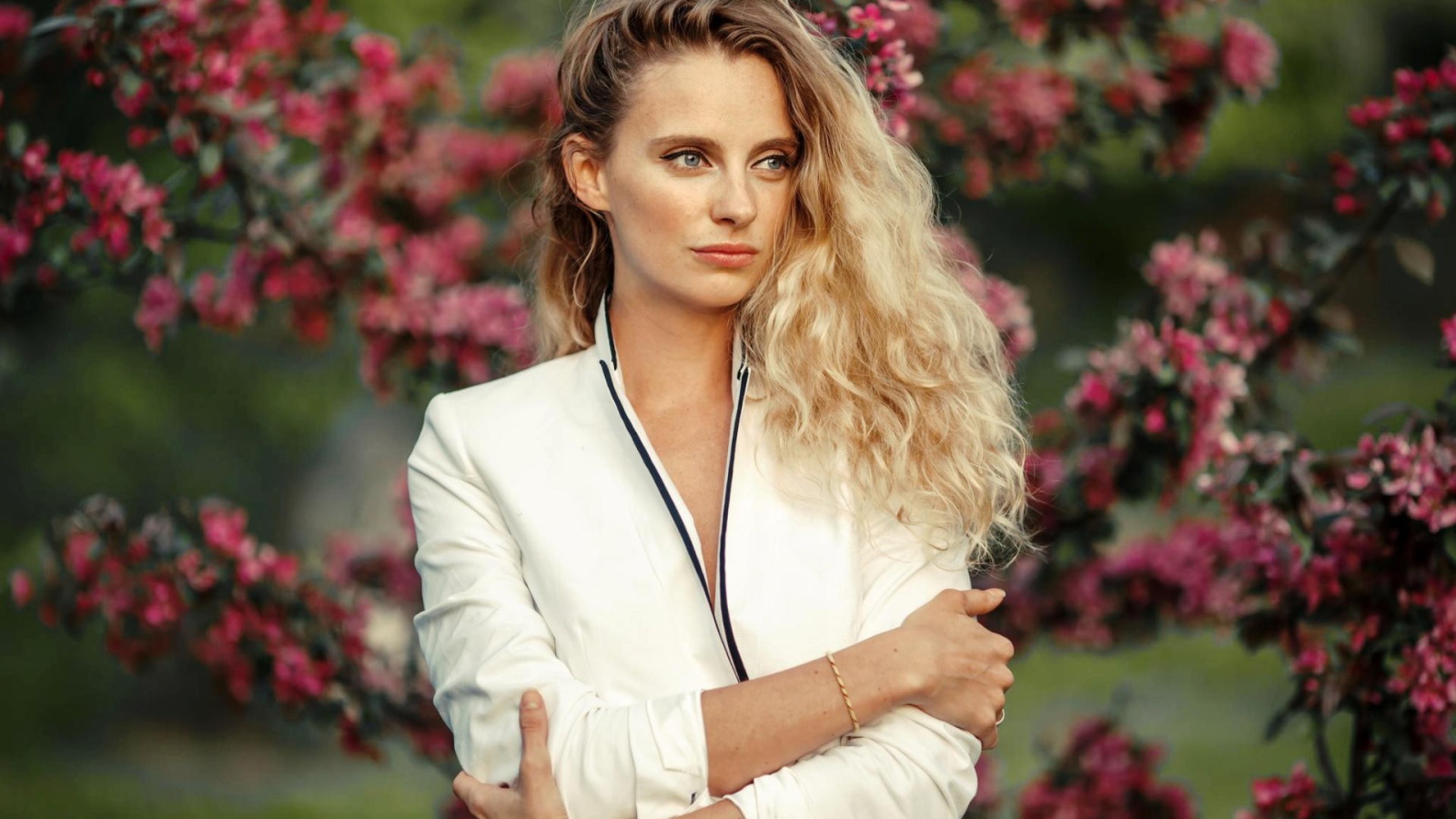 Голубоглазая блондинка на фоне цветущих деревьев