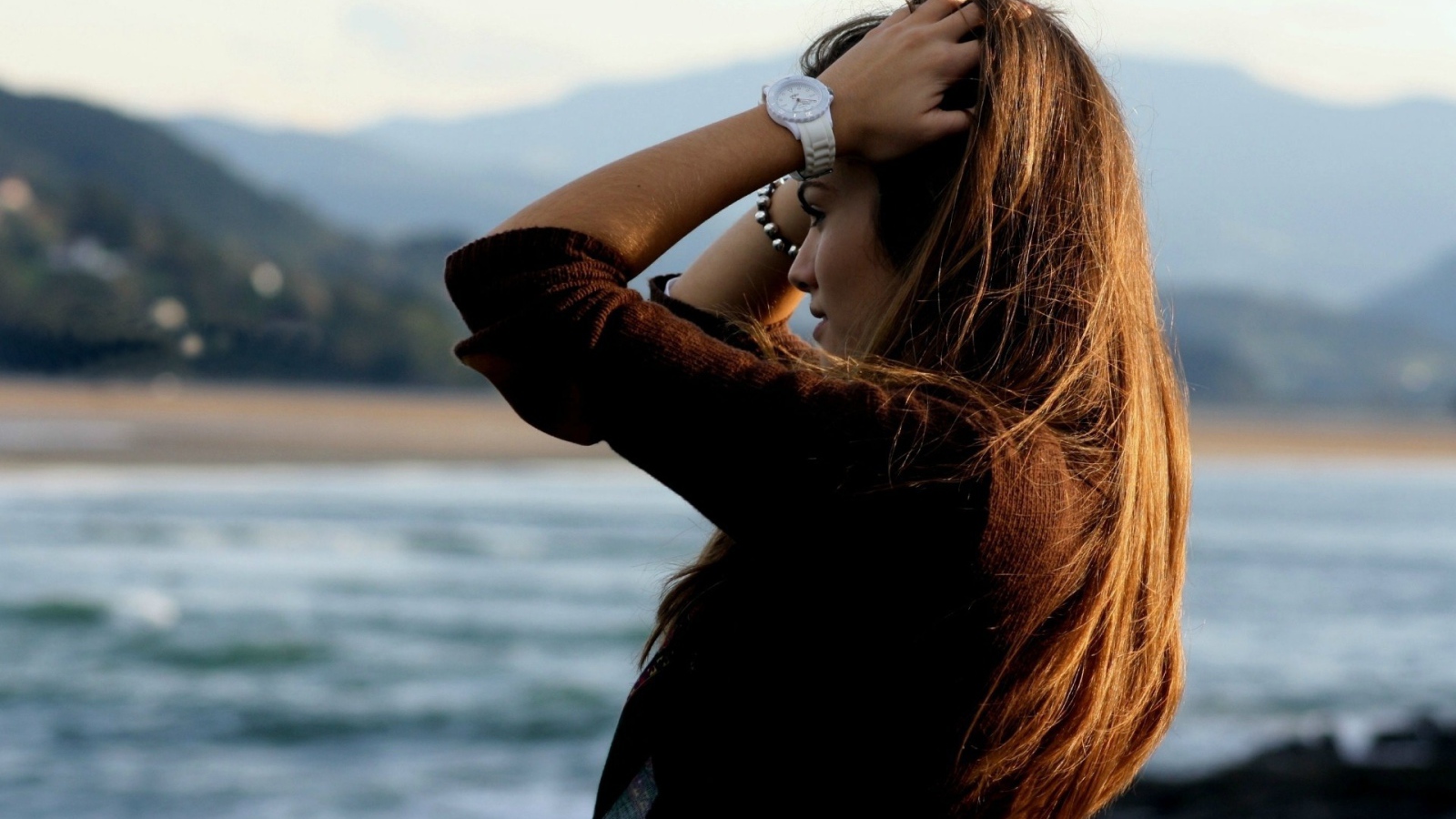 Шатенка с длинными волосами поправляет прическу