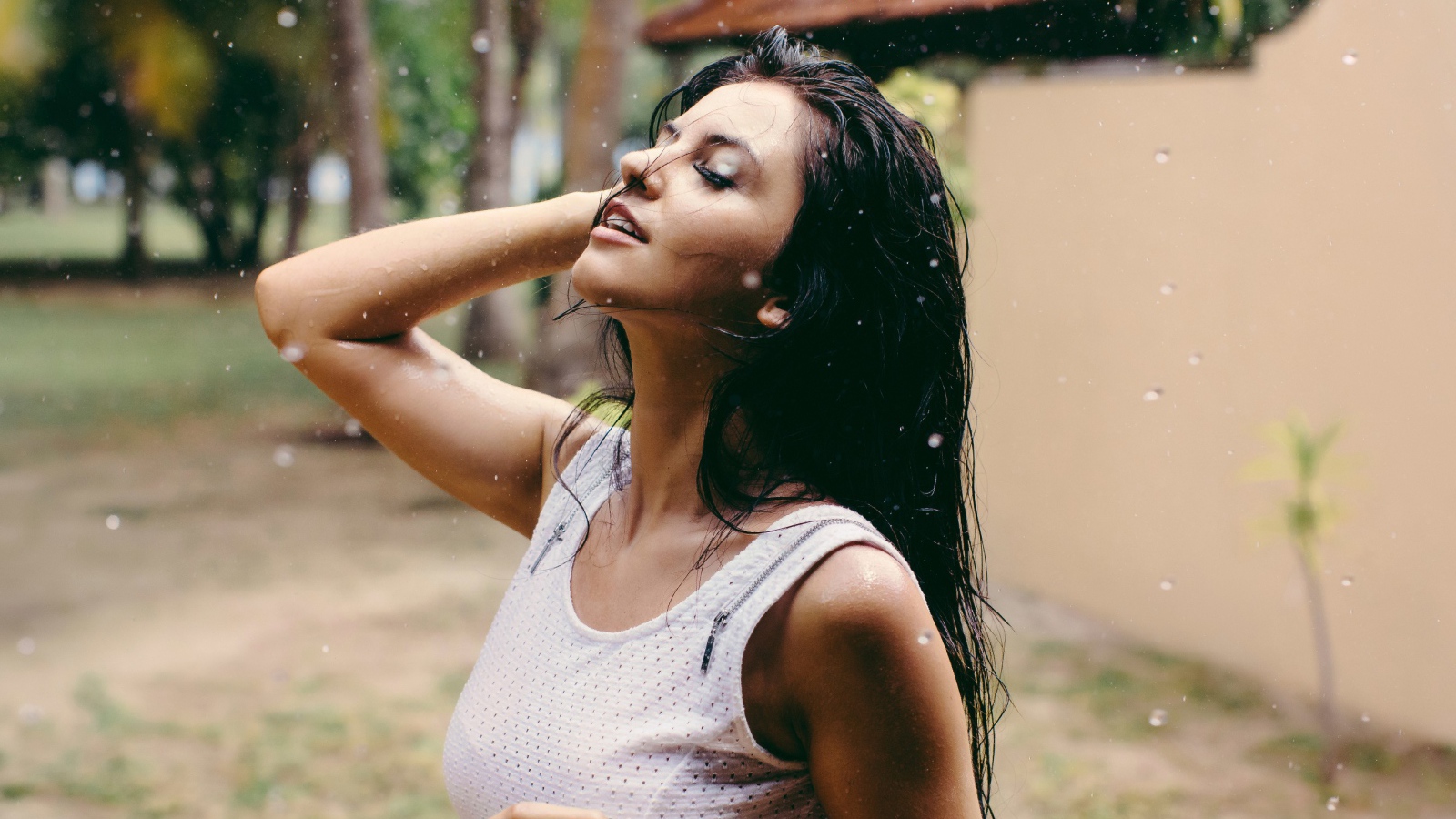 Брюнетка подставляет лицо под капли дождя