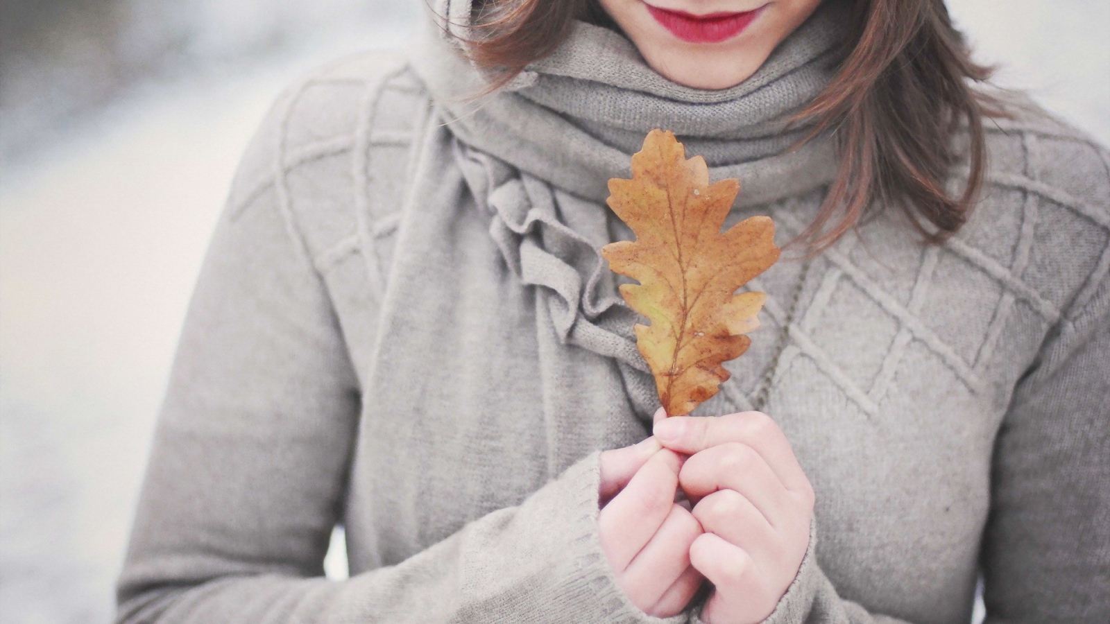 Девушка держит в руках желтый лист