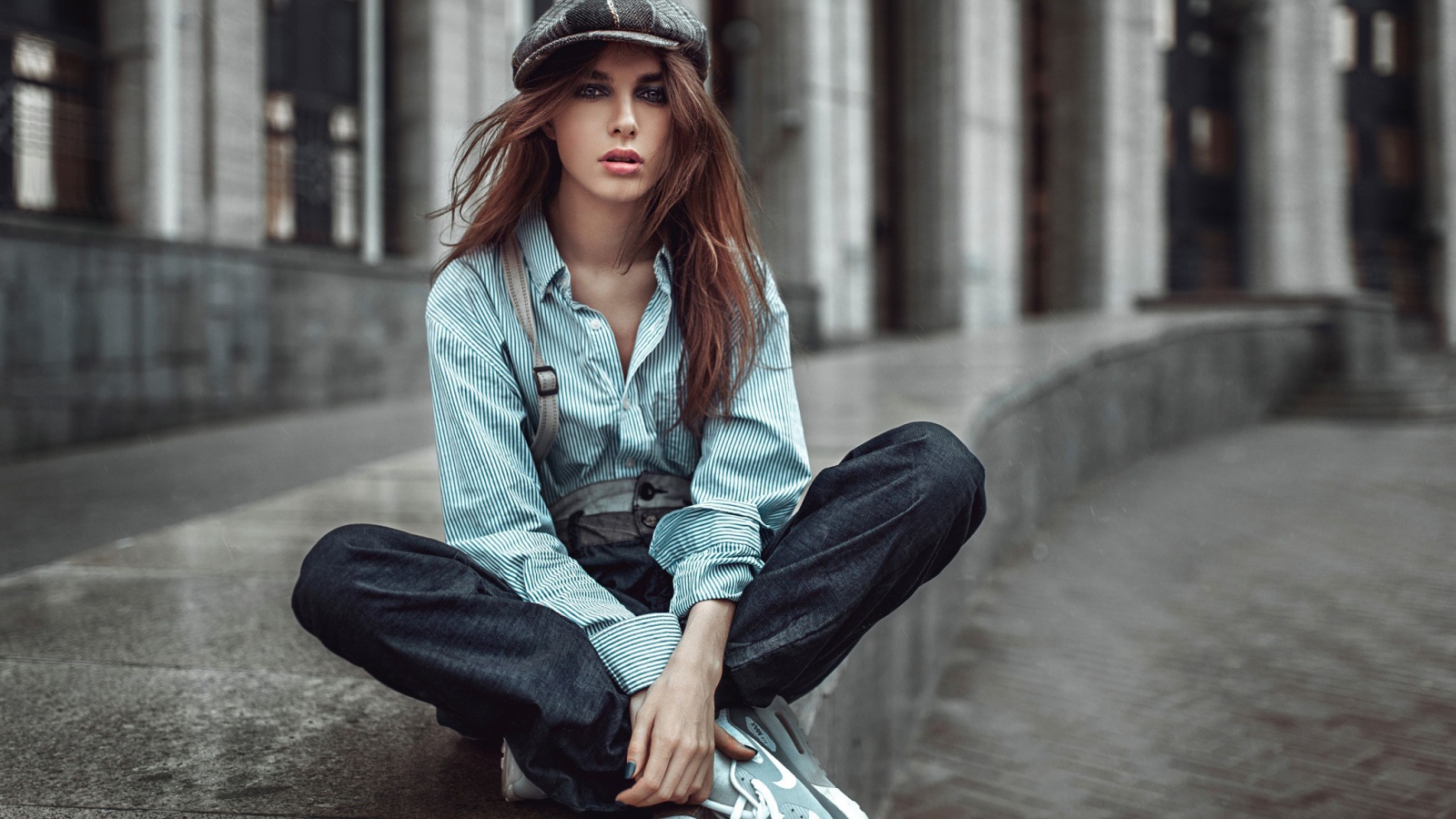 Девушка в берете сидит на краю дорожки