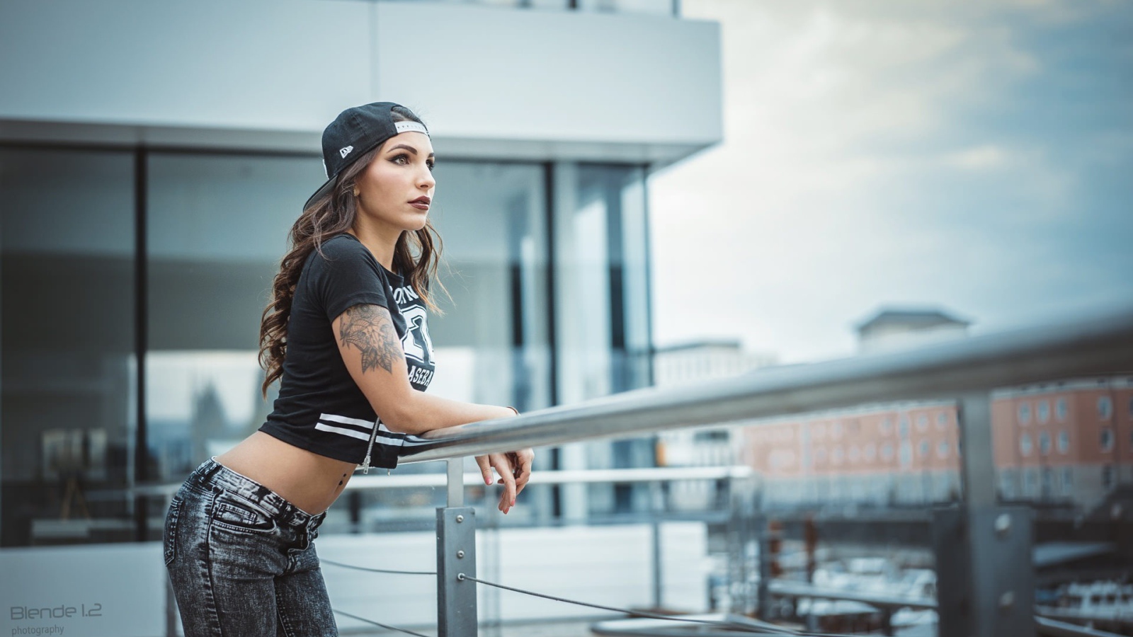 Девушка в кепке с тату смотрит на порт