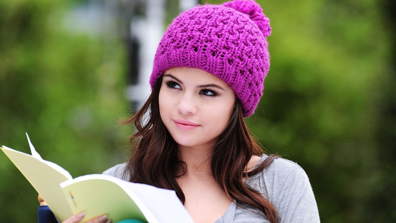 Девушка в сиреневой шапке читает книгу