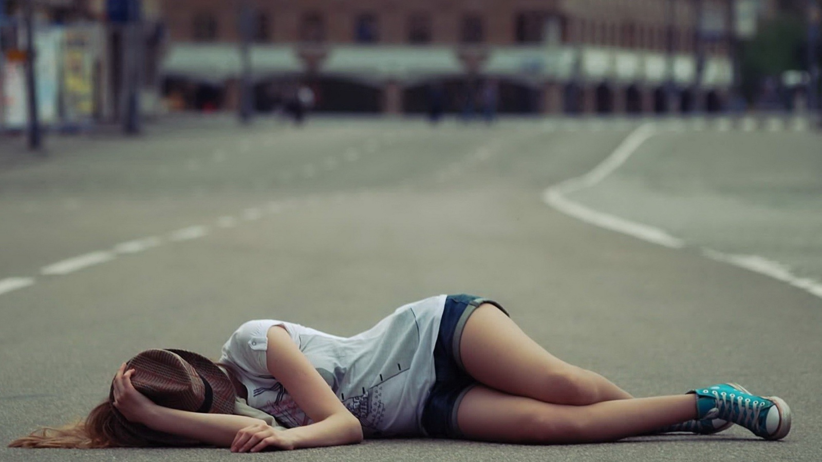 Девушка в шляпе лежит на дороге