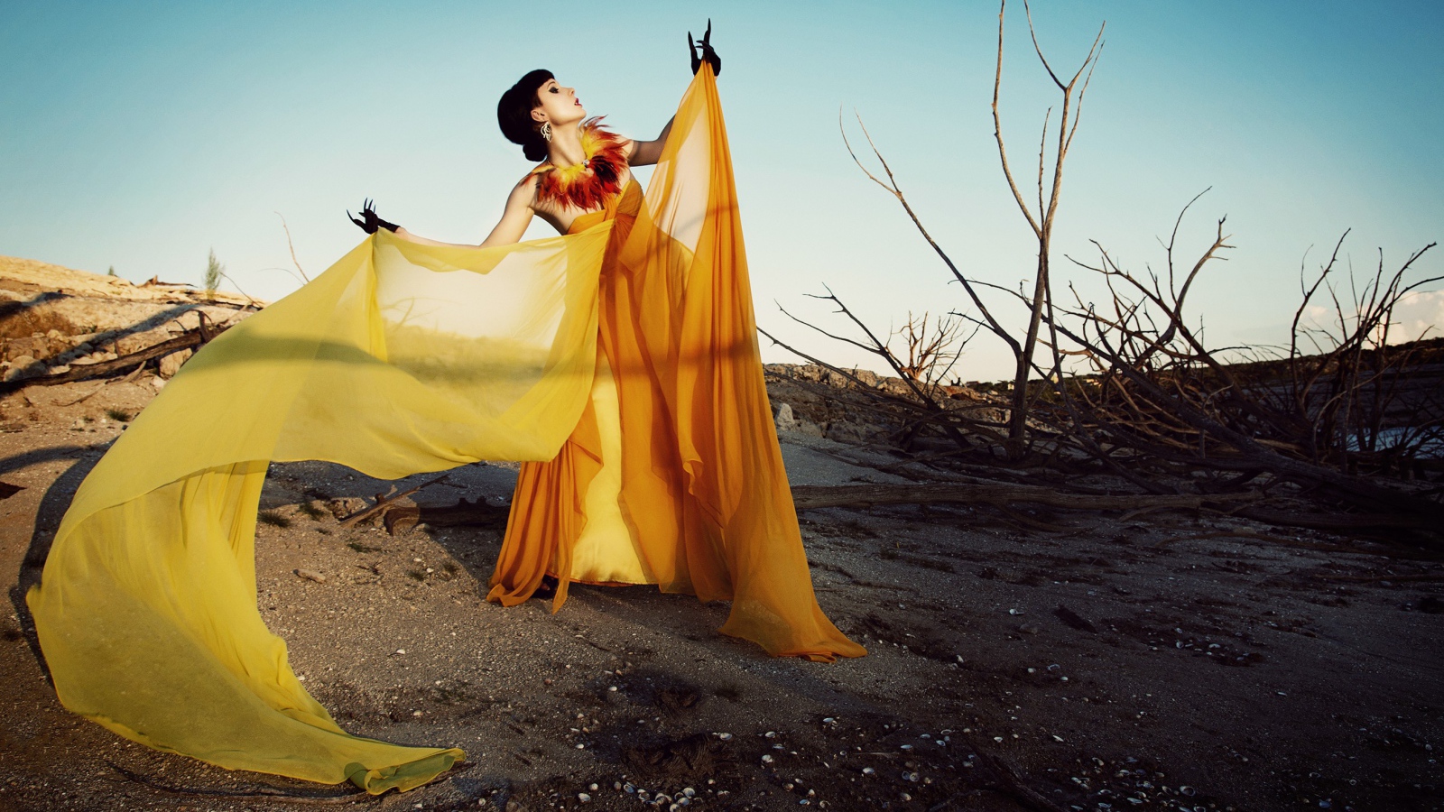 Девушка в оранжевом позирует в пустыне