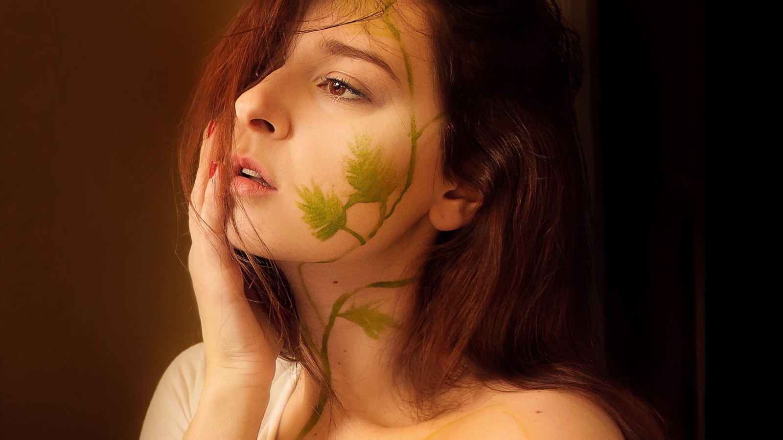 Рисунок зеленых листьев на лице и шее девушки