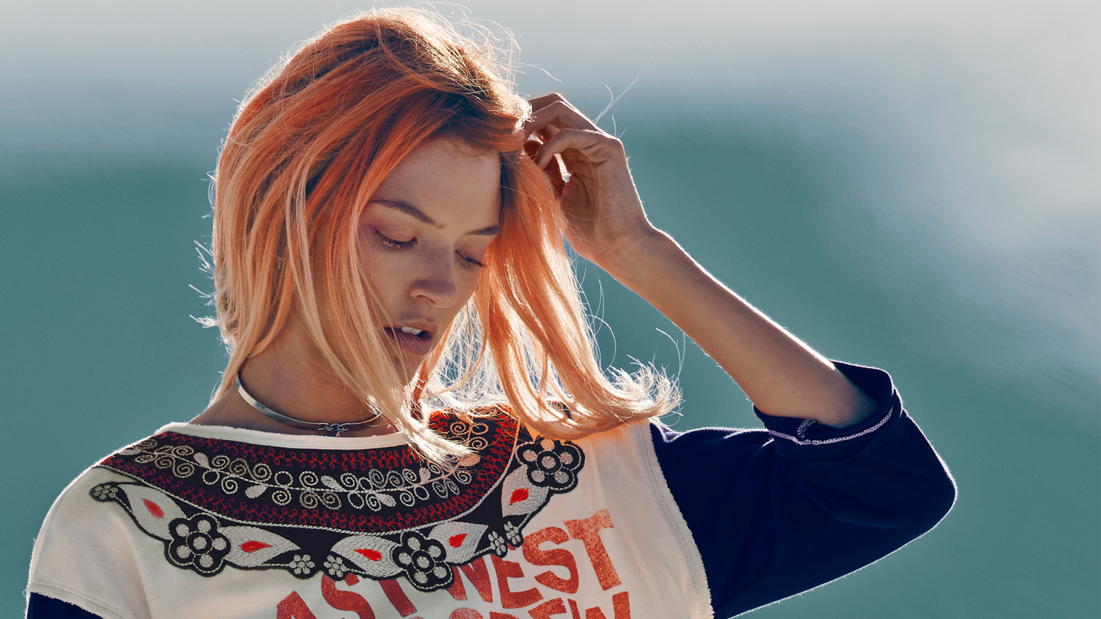 Рыжая девушка на ветру поправляет волосы