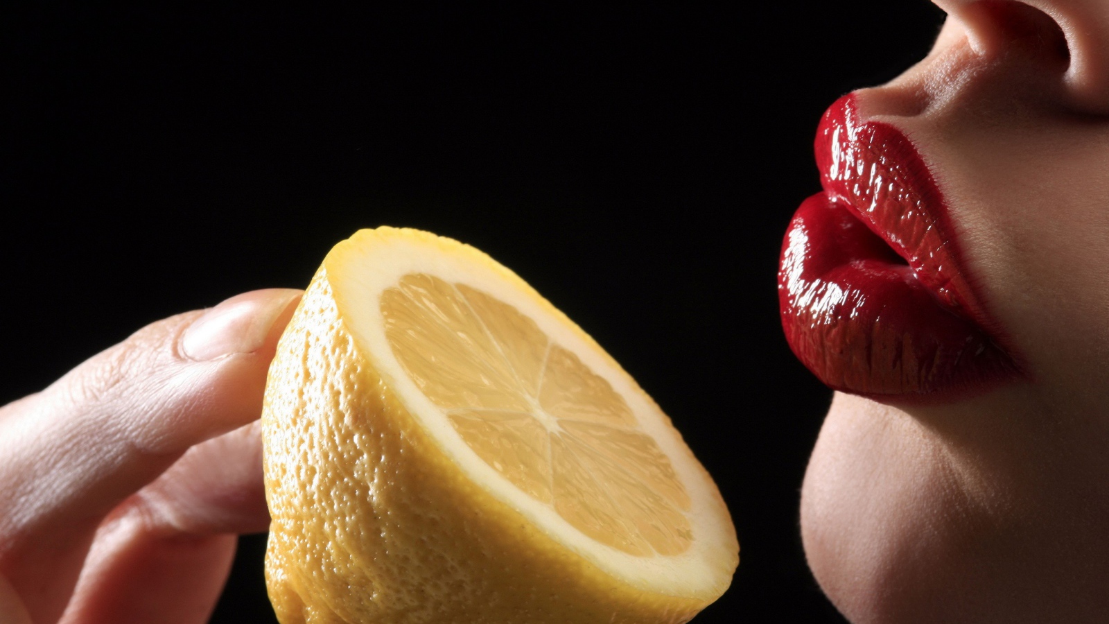 Девушка поднесла лимон к губам