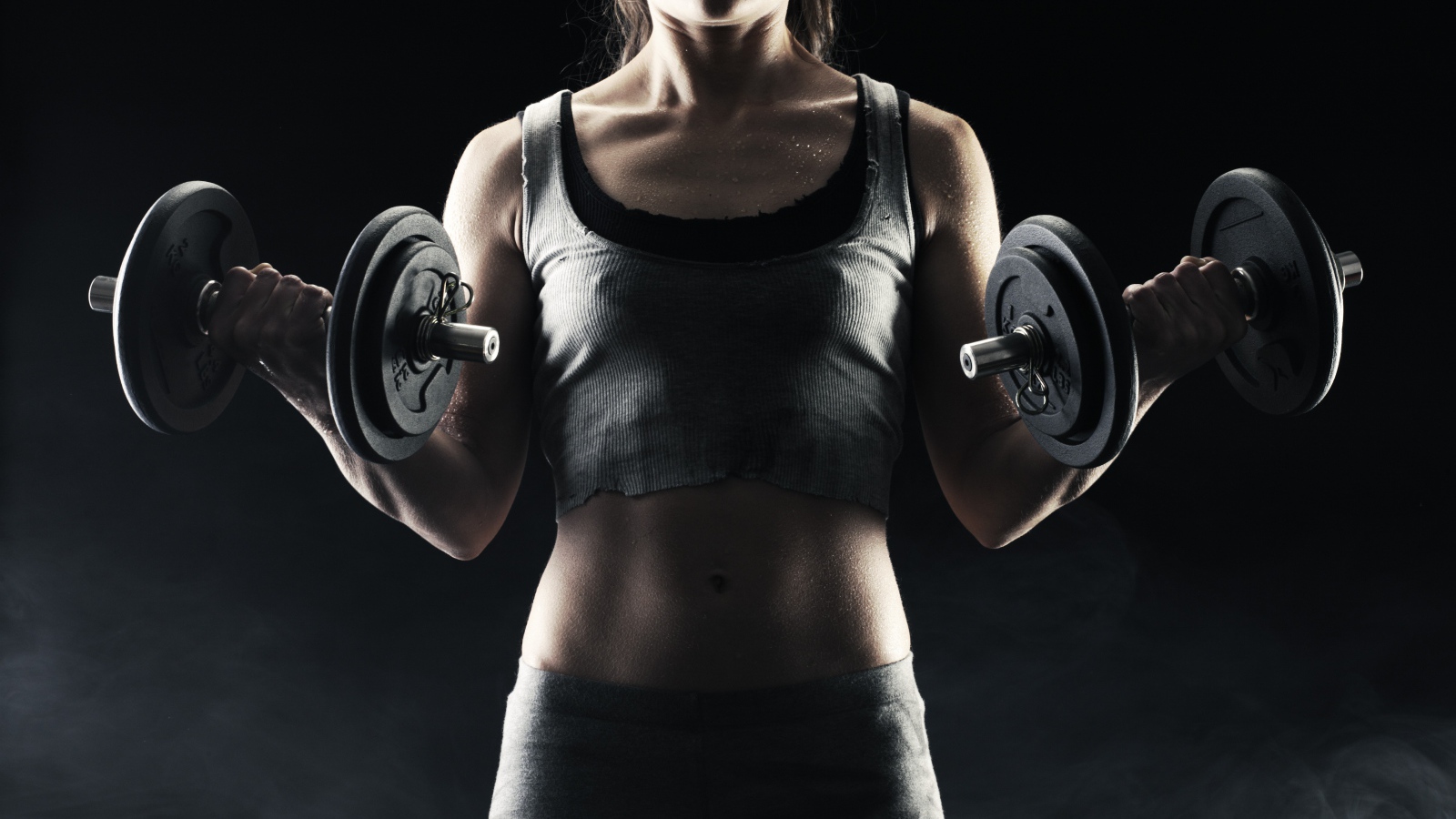 Спортивная девушка с гантелями в руках