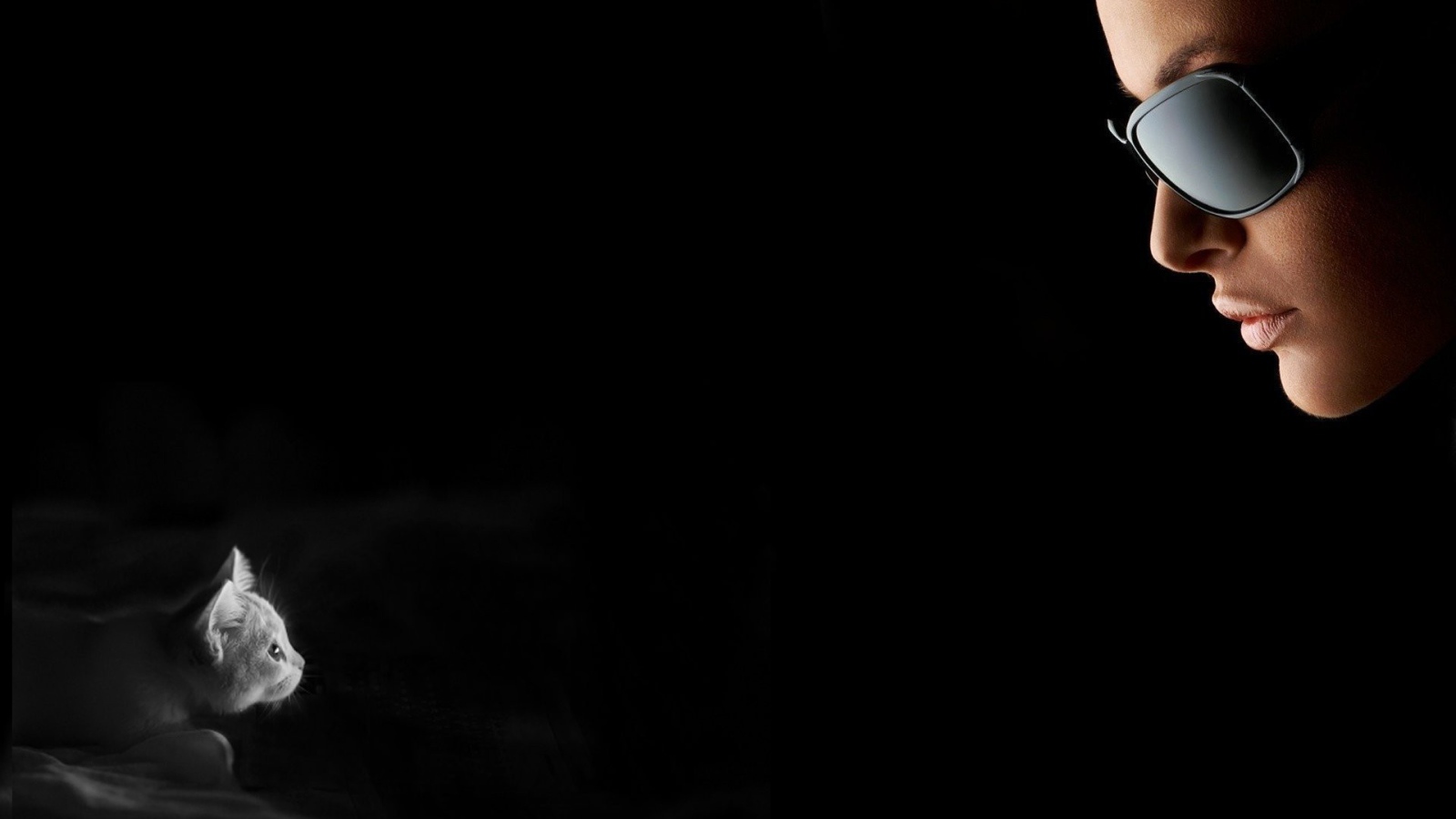 Девушка смотрит на котенка, черный фон