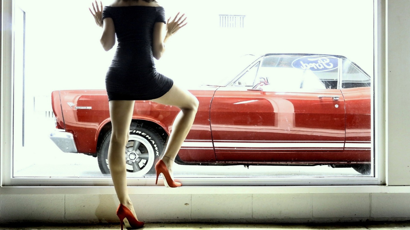 Девушка смотрит в окно на красный автомобиль