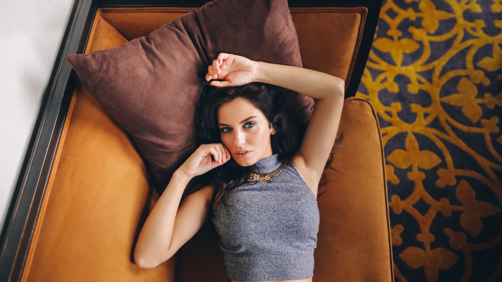 Модель Aurela Skandaj лежит на диване