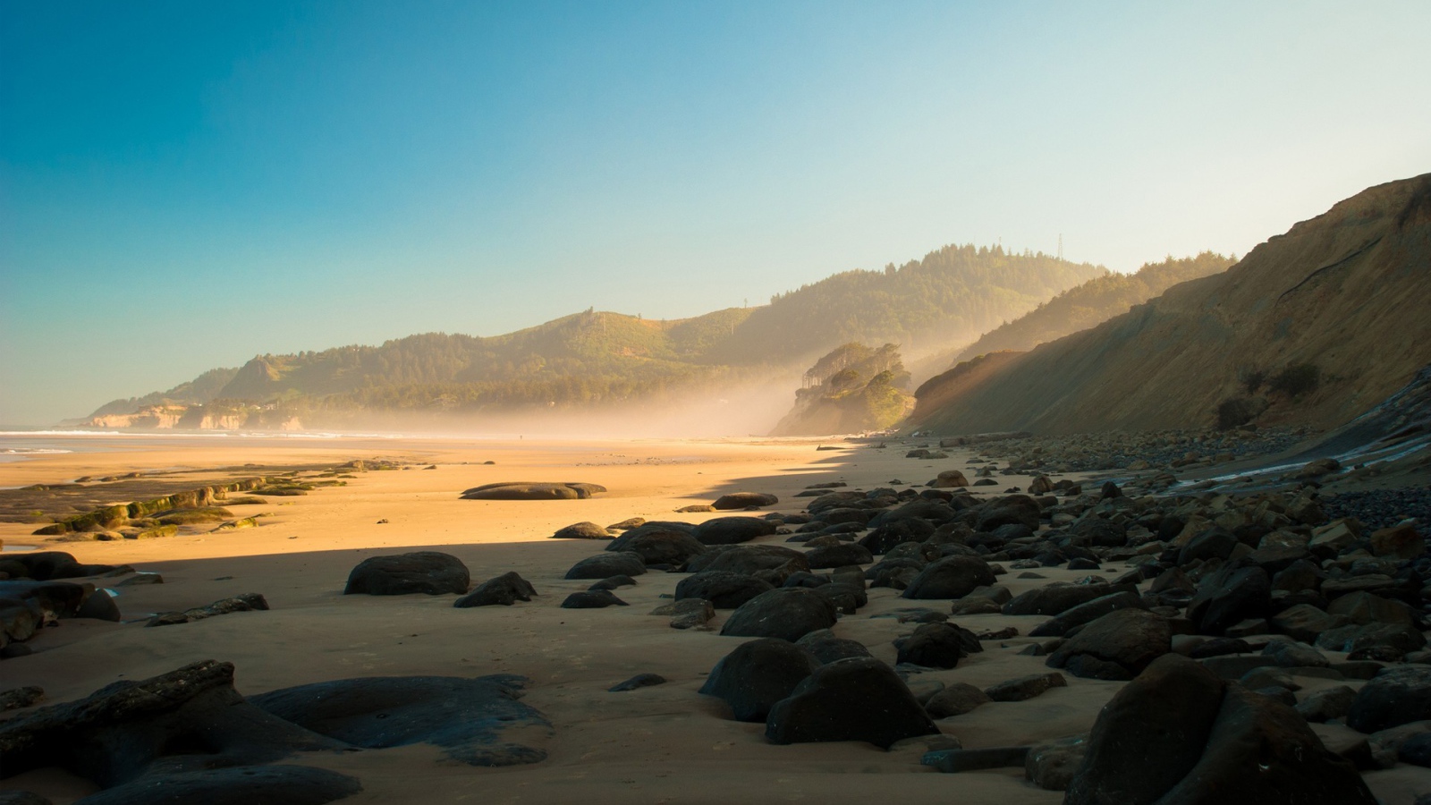 Черные круглые камни на песке пляжа