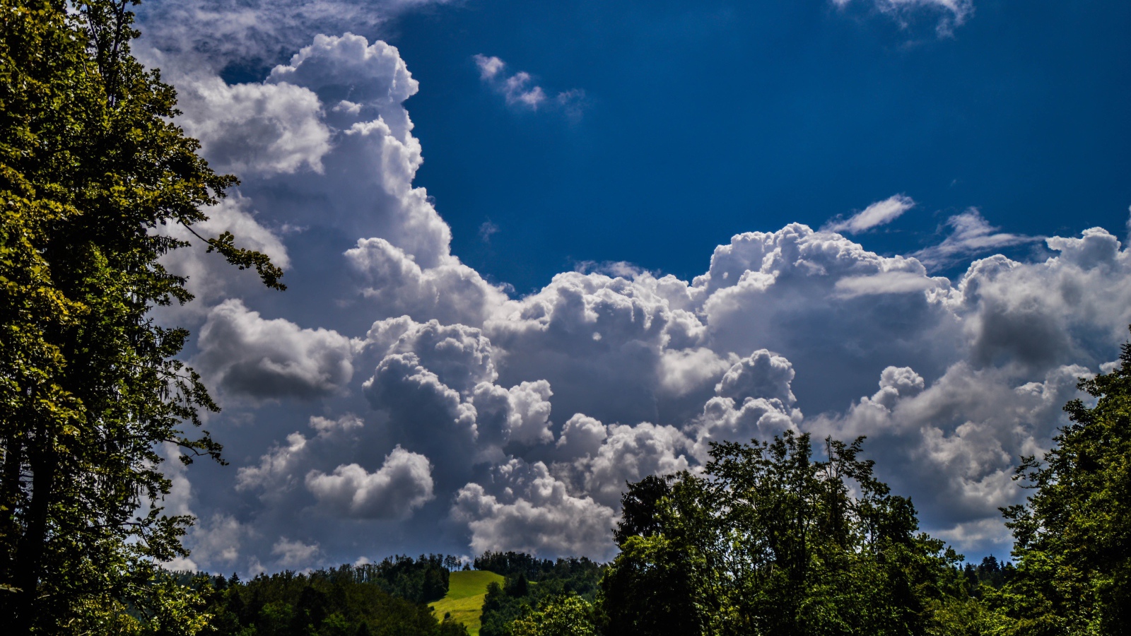 Кучевые облака над зелеными холмами