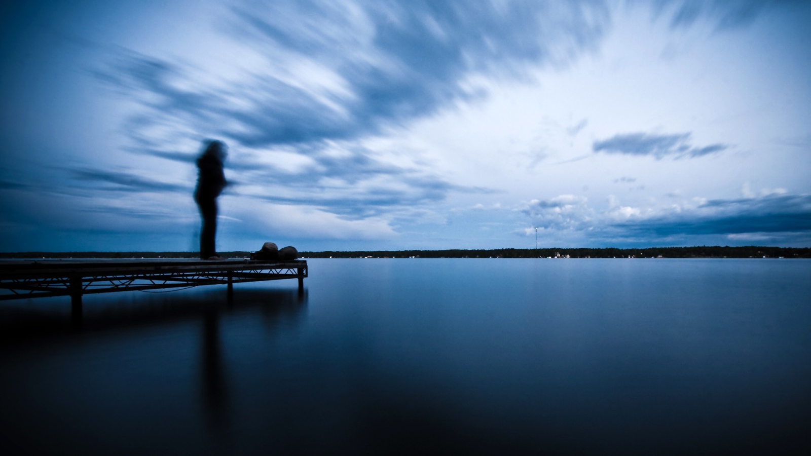 Силуэт человека на пристани у озера