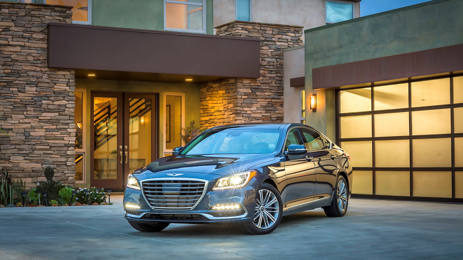 Серебристый автомобиль Genesis G80 с включенными фарами