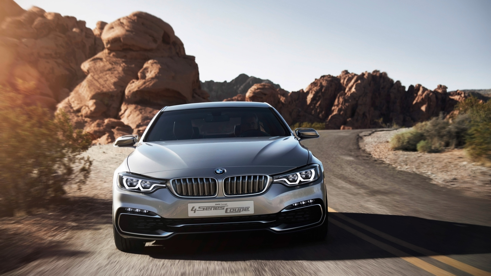 Серебристый автомобиль BMW 4 Series Coupe на дороге у скал