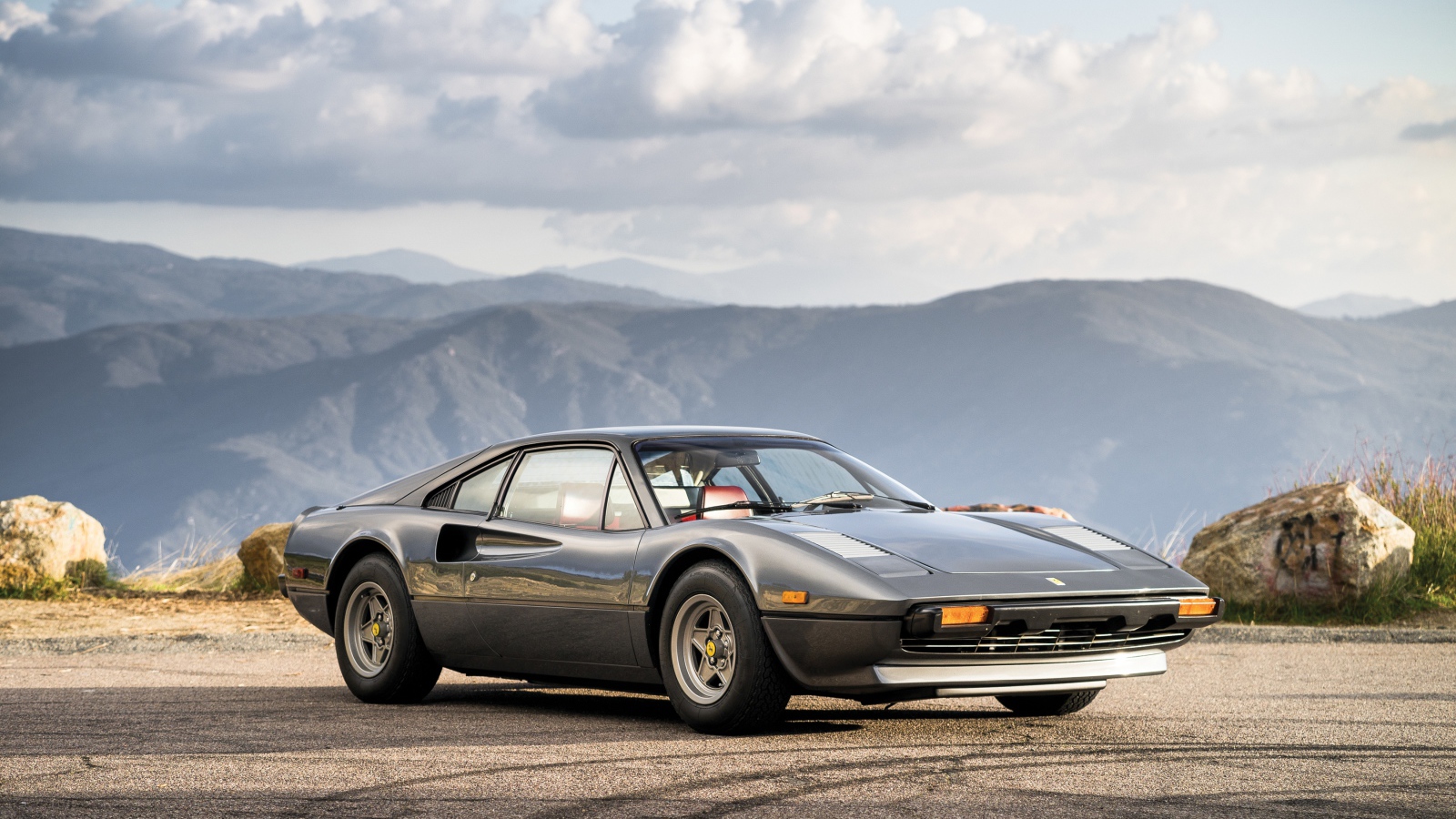 Суперкар Ferrari 308 gts серого цвета,   на фоне гор 