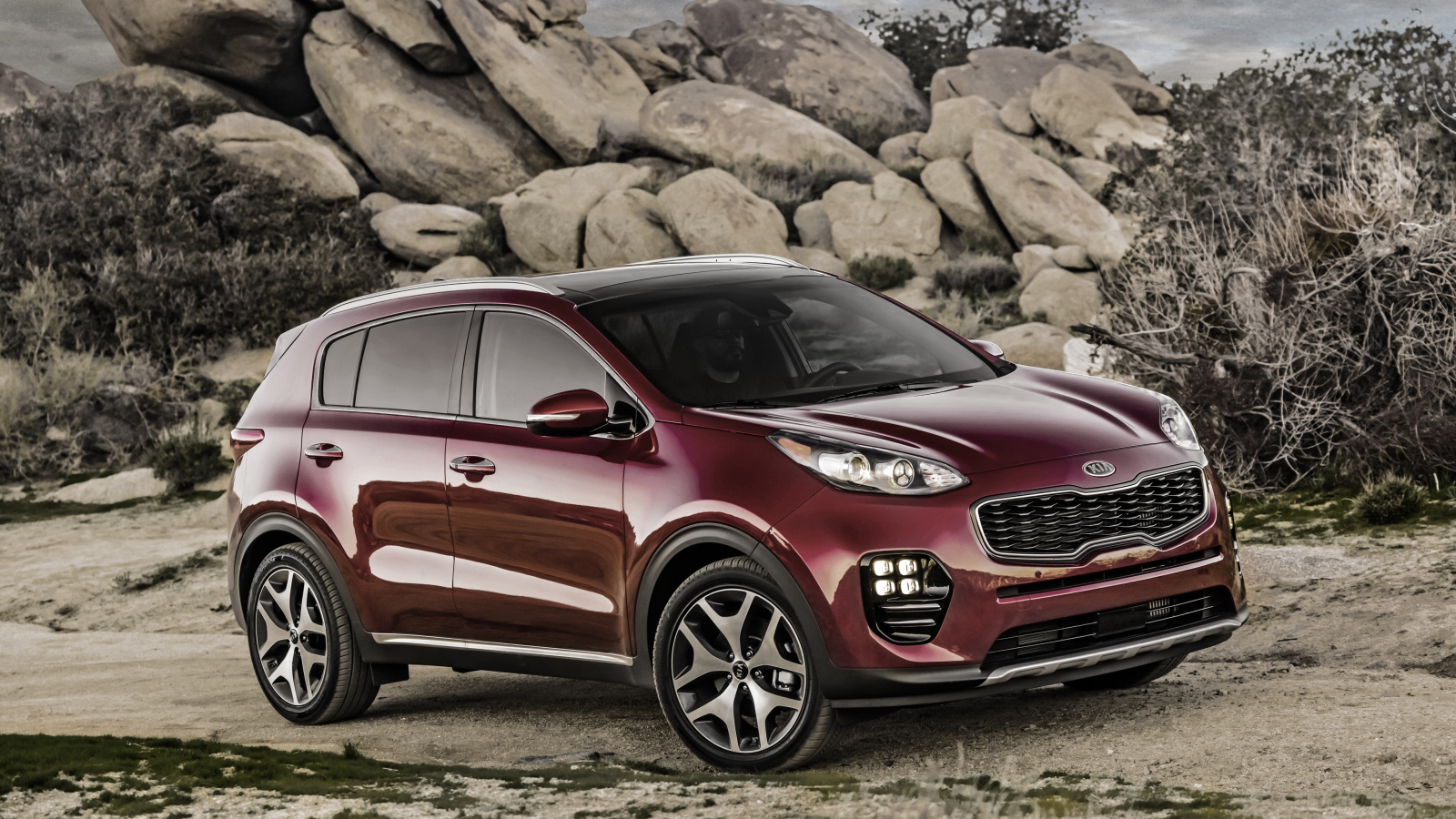 Стильный бордовый внедорожник Kia Sportage на фоне больших камней