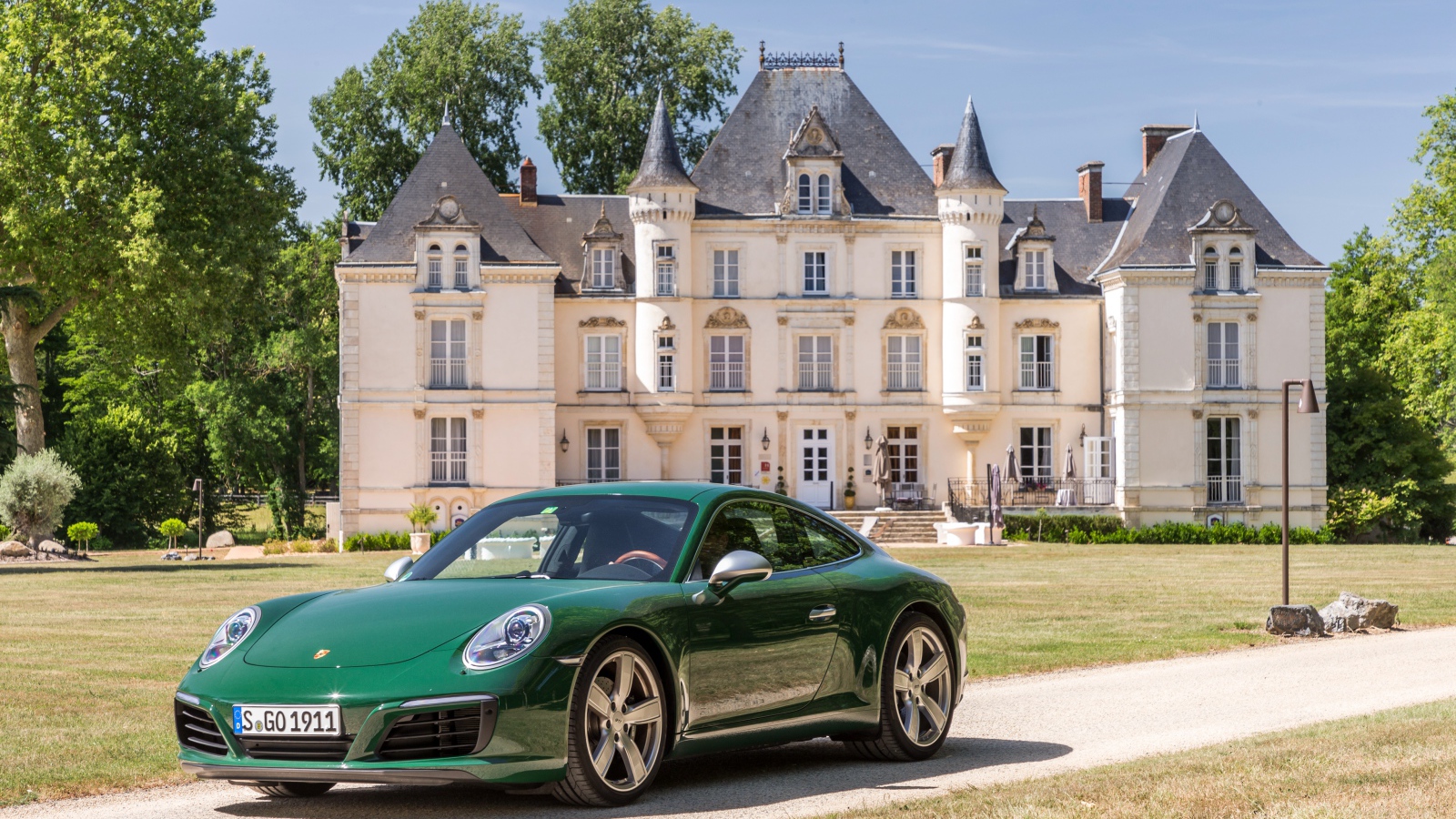 Зеленый спортивный автомобиль Porsche 911 Carrera на фоне дома