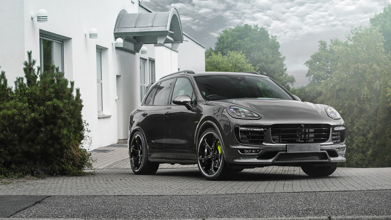 Серебристый автомобиль Porsche Cayenne стоит у дома