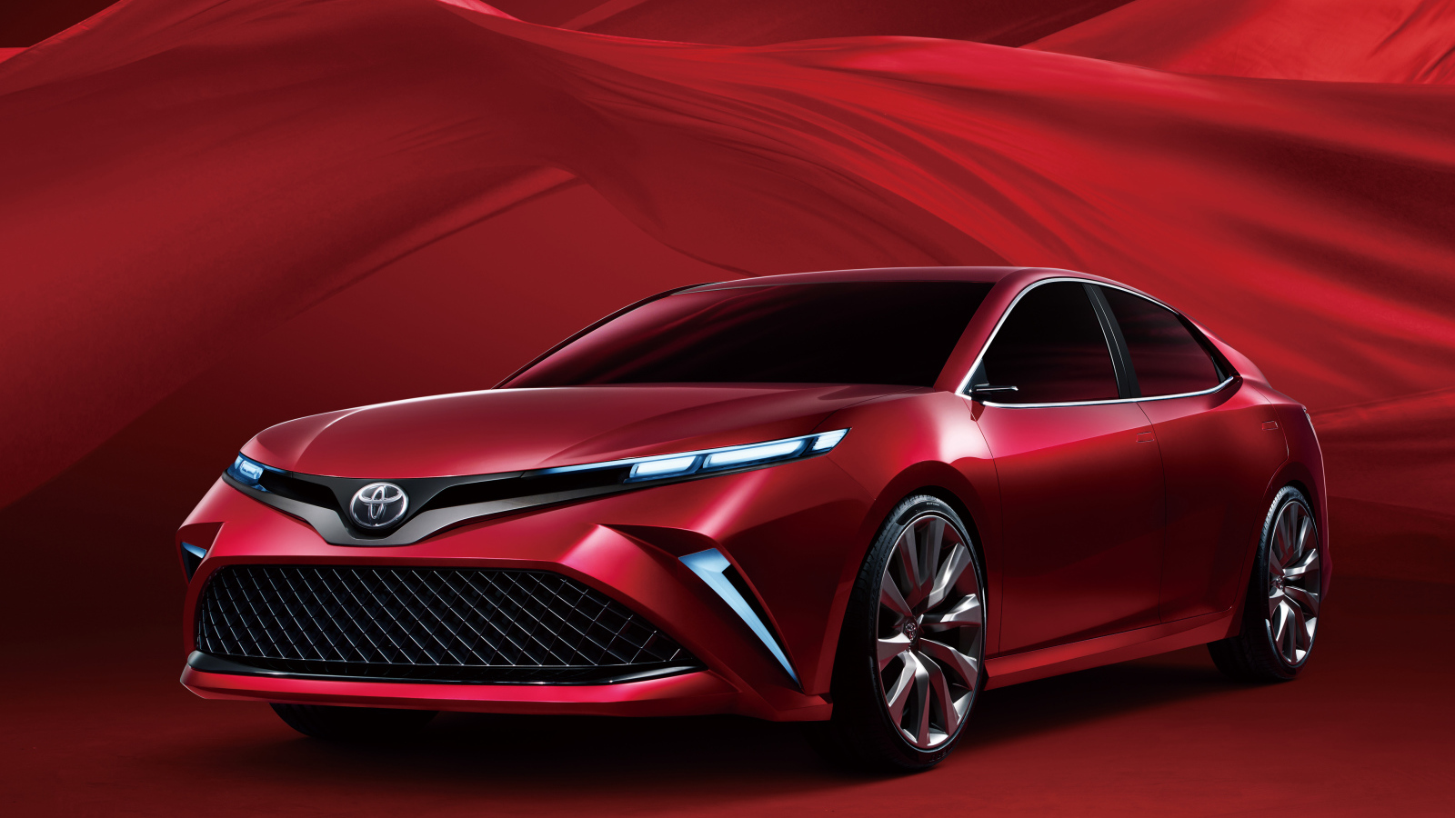 Красный автомобиль Toyota Camry, 2017 года на красном фоне 