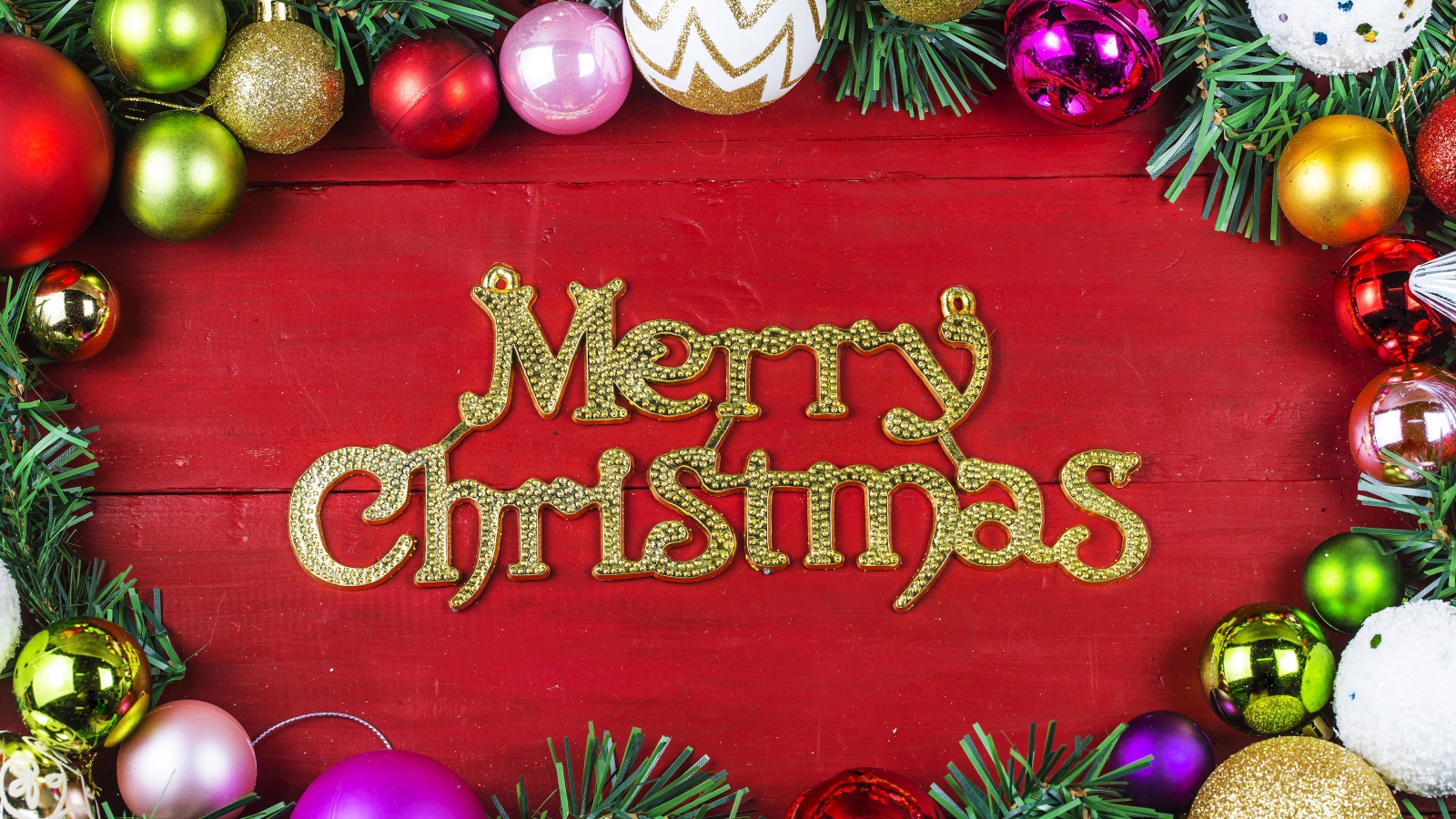 Надпись Merry Christmas на красном фоне с елочными игрушками на Рождество