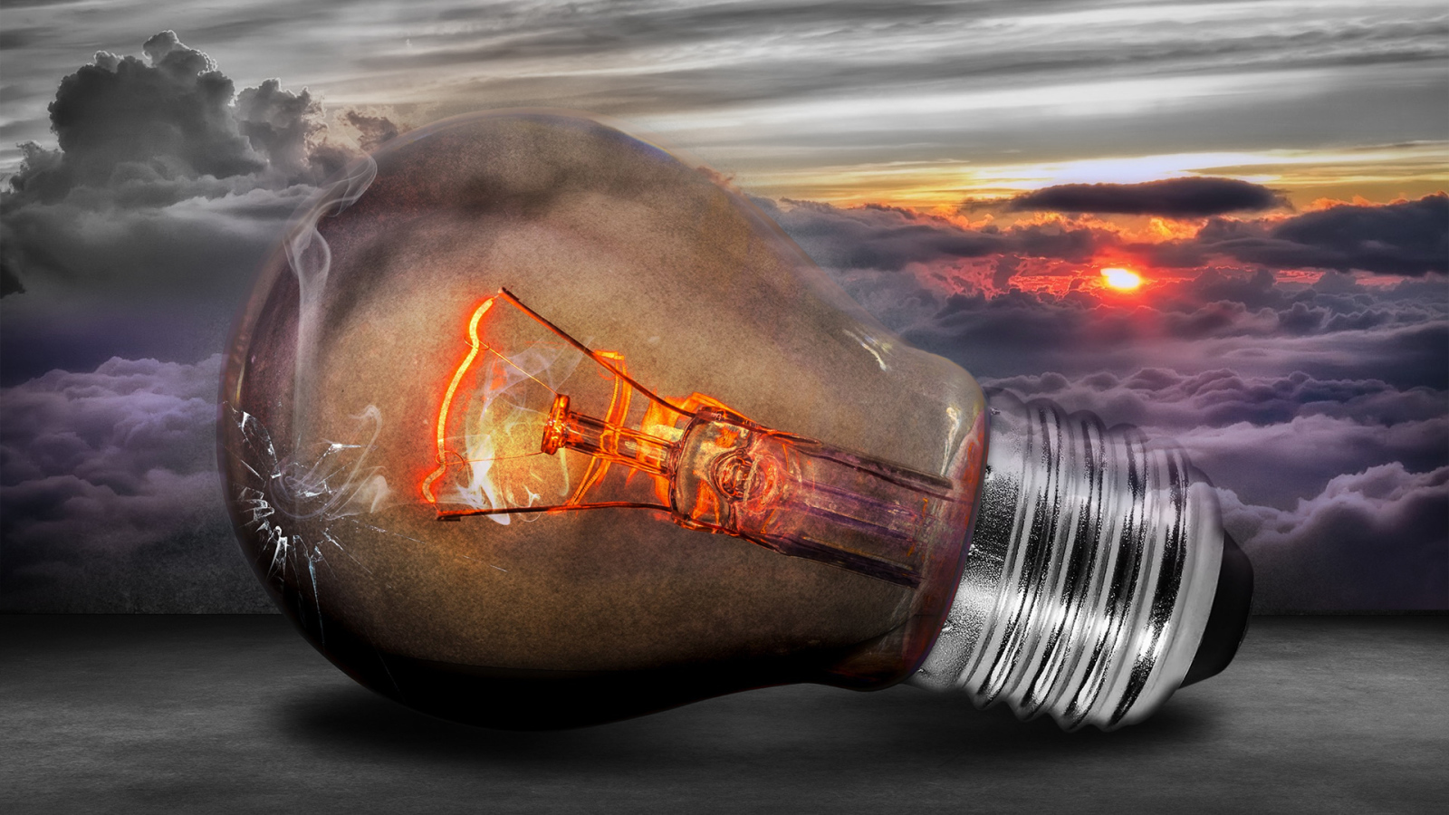 Раскаленная лампочка на фоне белых облаков в небе