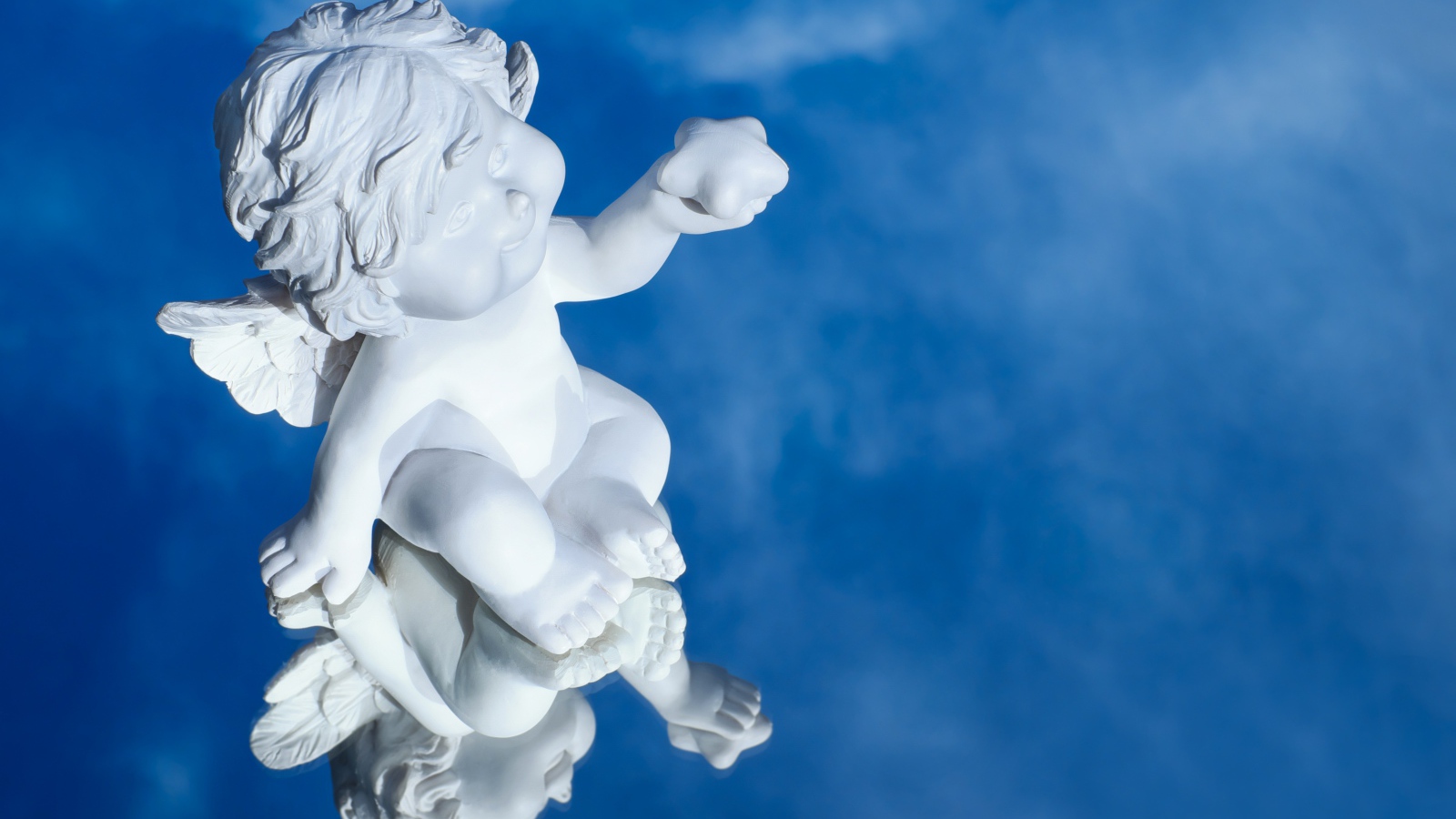 Маленькая статуя купидона отражается в голубой поверхности
