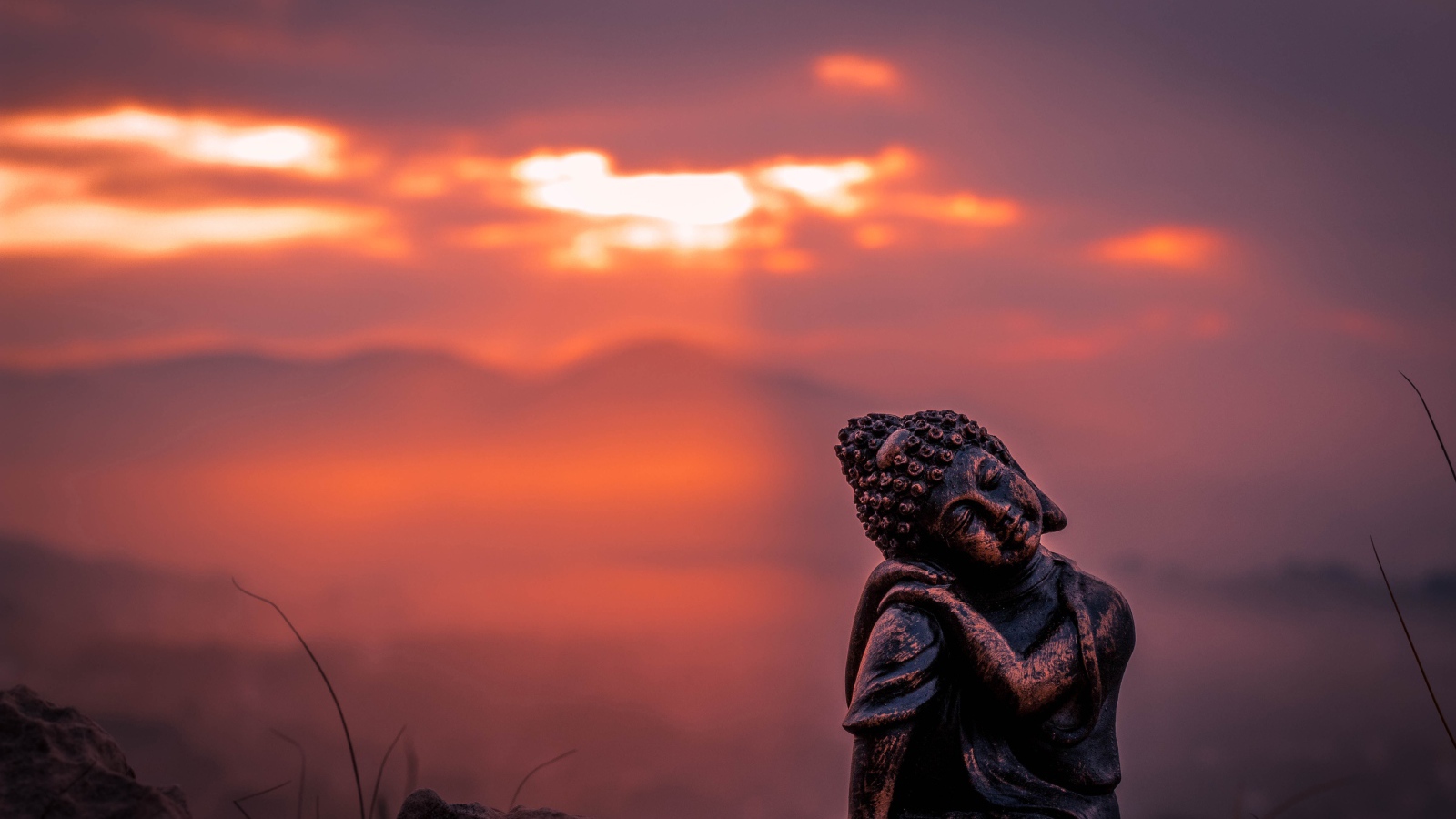 Статуя Будды на фоне солнца на закате