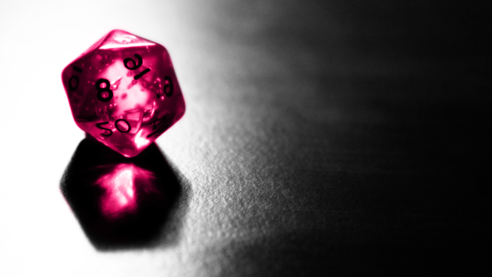 Розовый фигурный кубик отражается серой поверхности стола