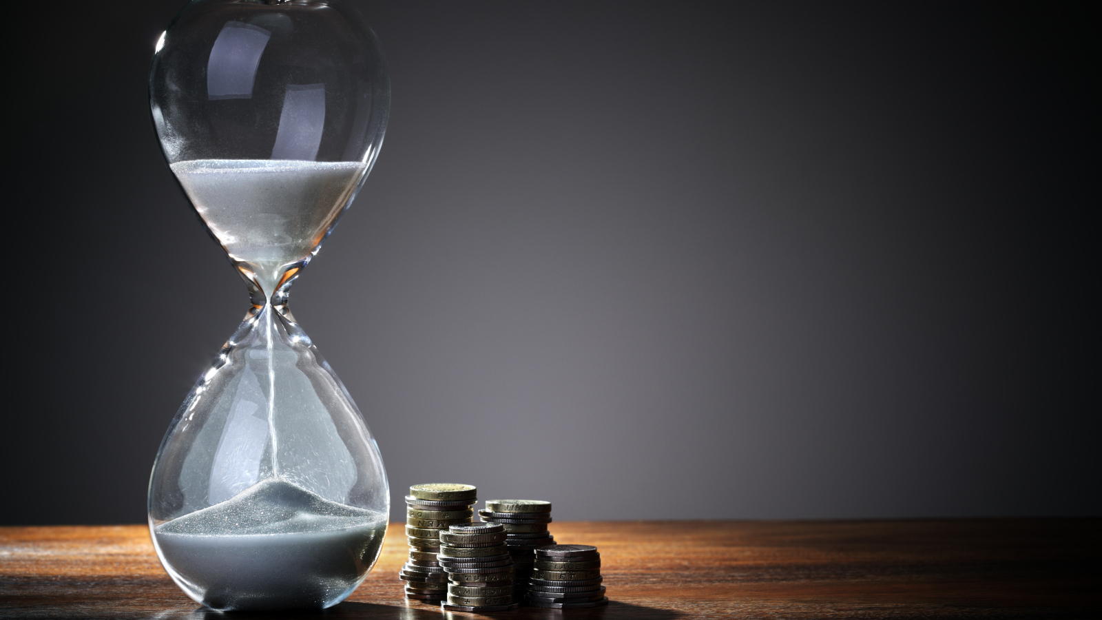 Монеты и песочные часы на столе