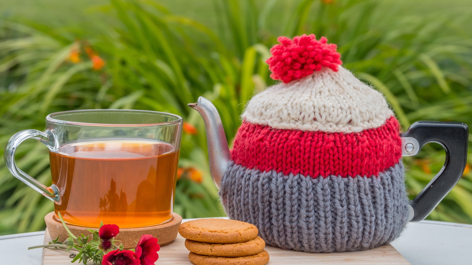 Чайник с чашкой чая на столе с печеньем и цветами