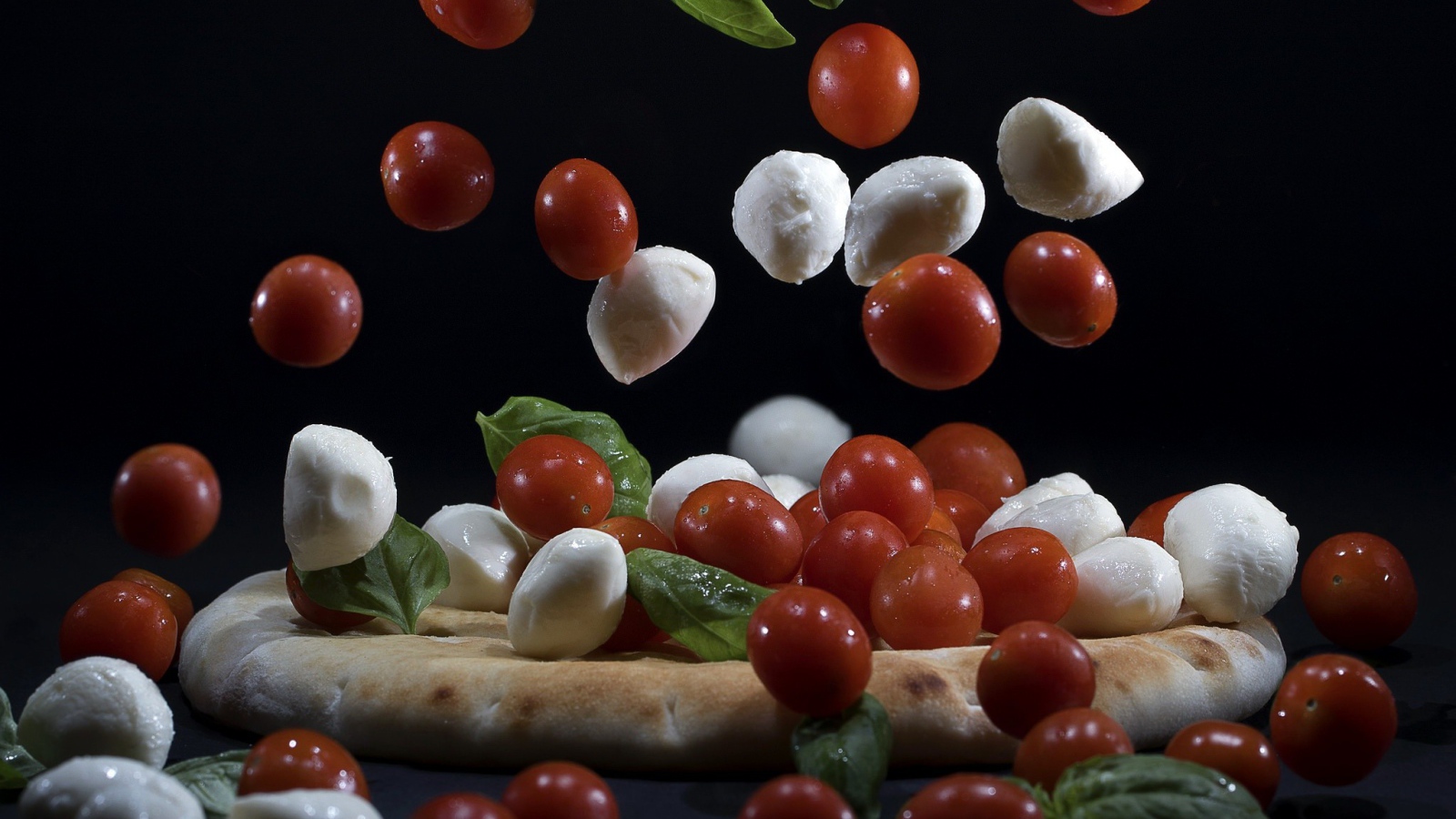 Помидоры и сыр Моцарелла падают на пиццу 