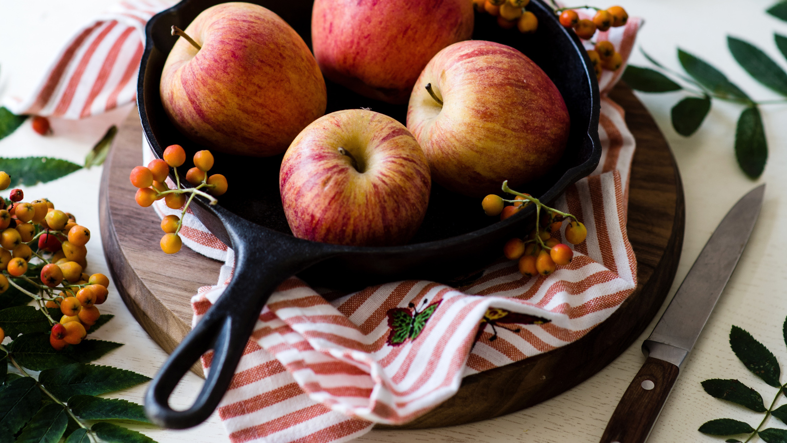 Красивые красные яблоки на сковороде с ягодами рябины