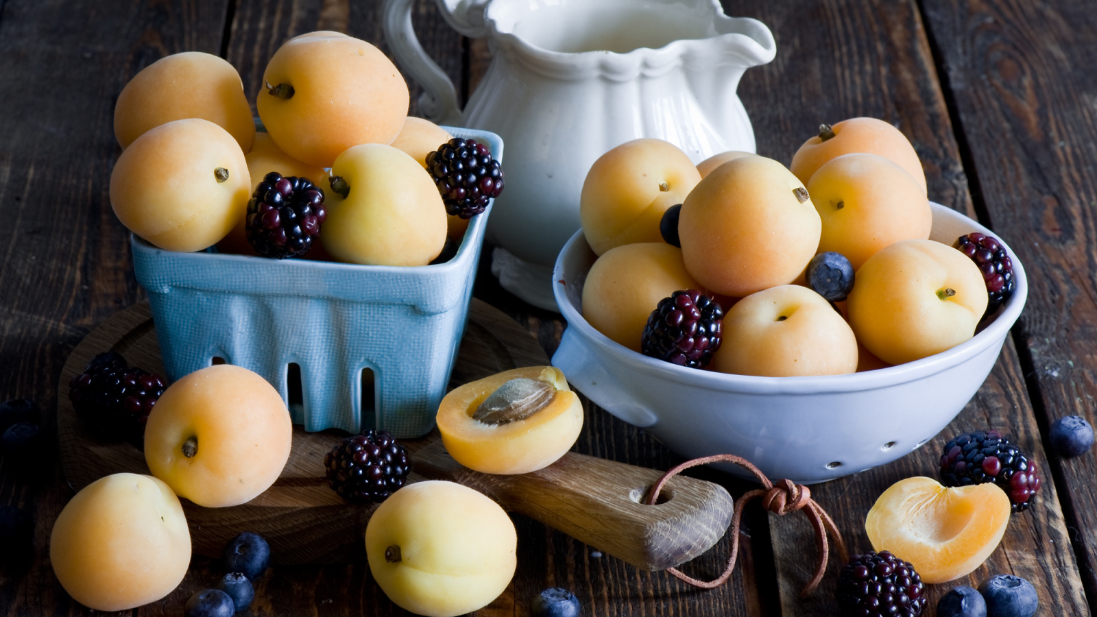 Спелые абрикосы и ягоды на столе 